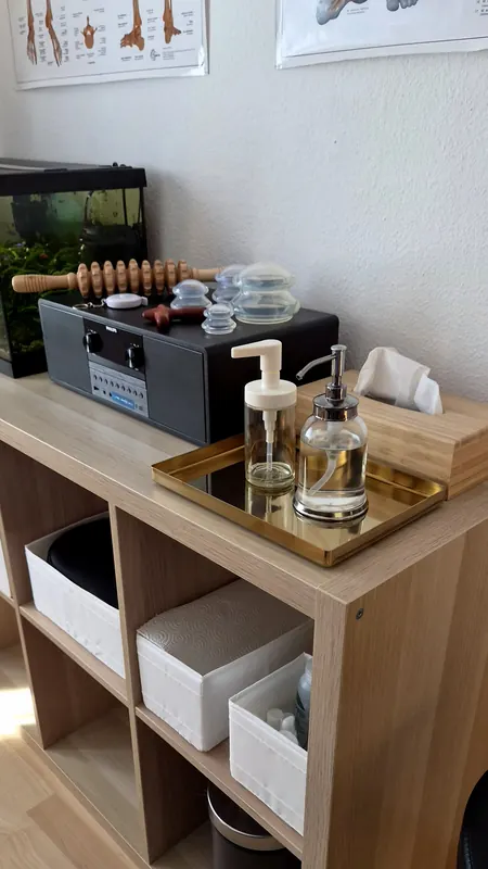 Ablage mit Schröpfgläsern, Massageroller, Öl und Musikanlage